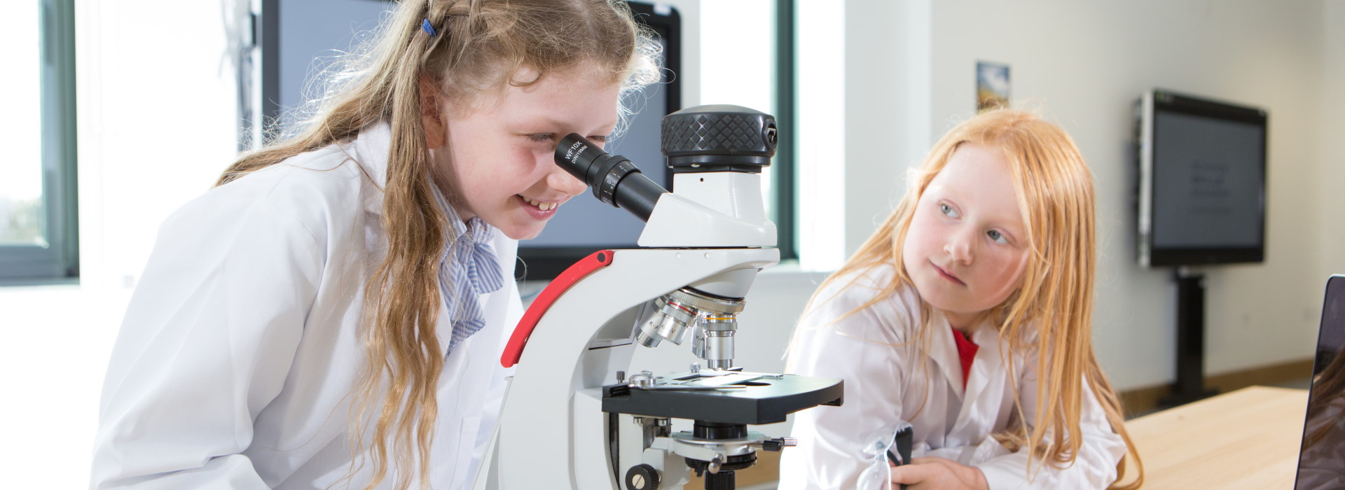 Girls with microscope in STEM Hub at Inverness Campus